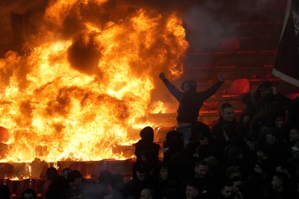 Partizan fans cheer in front of burning seats during a Serbian league soccer derby match between Red Star and Partizan in Belgrade, Serbia, Feb. 22, 2026. (AP Photo/Darko Vojinovic, File)