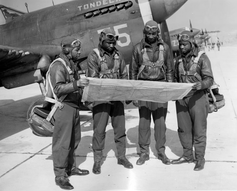 Tuskegee Airmen studying maps before flying a fighter plane