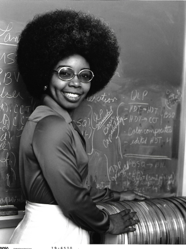 Valerie_L._Thomas_standing_with_a_stack_of_early_Landsat_Computer_Compatible_Tapes_-_Original.png