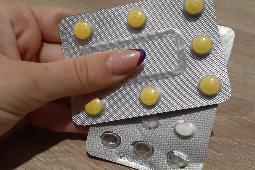 two packets of pills being held by a female hand