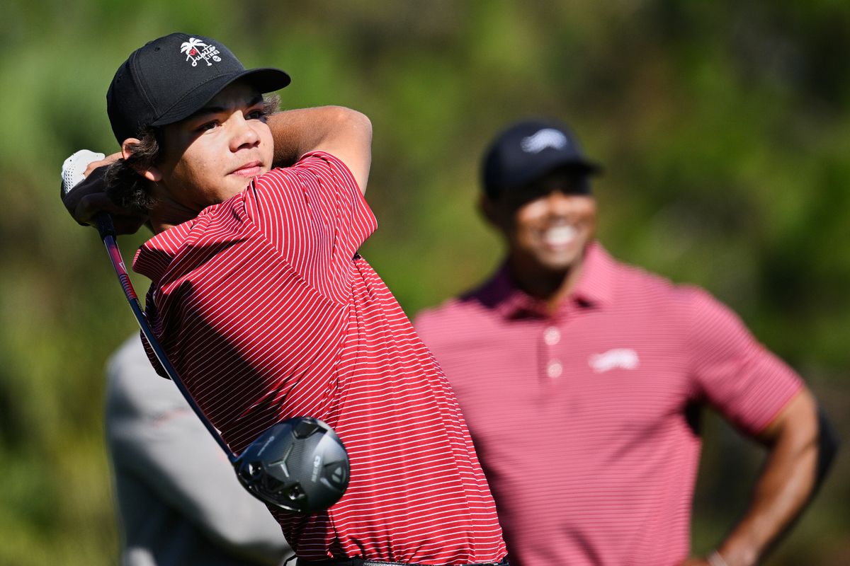 Charlie Woods tees off on the fifth hole as his father Tiger Woods watches during the final round of the PNC Championship golf tournament