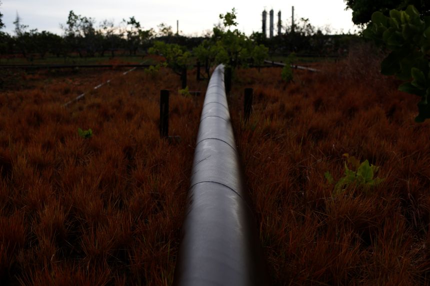 An oil pipeline from petroleum plant crosses a field on the outskirts in El Tigre, Venezuela, as seen on June 2, 2019.