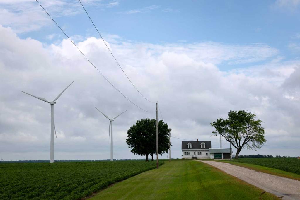 Photo of a farm house surrounded by fields. Two wind turbines are visible. 
