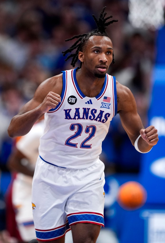 Kansas basketball player Dajuan Harris Jr. in a white jersey with "KANSAS" and "22" in blue, clenching his fists on the court.