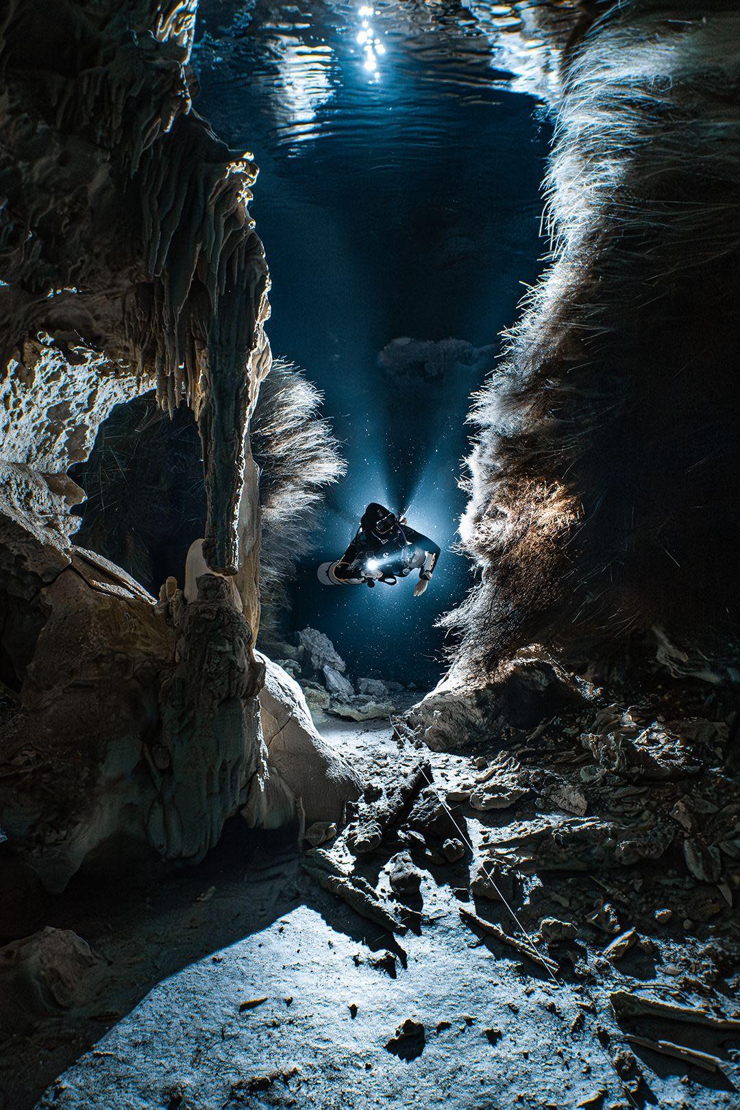 A scuba diver shines a torch light as they swim in the Cenotes in Dos Pisos, Mexico.