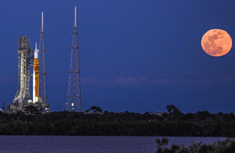 A full moon rises as the Space Launch System (SLS) rocket is set to be launched.