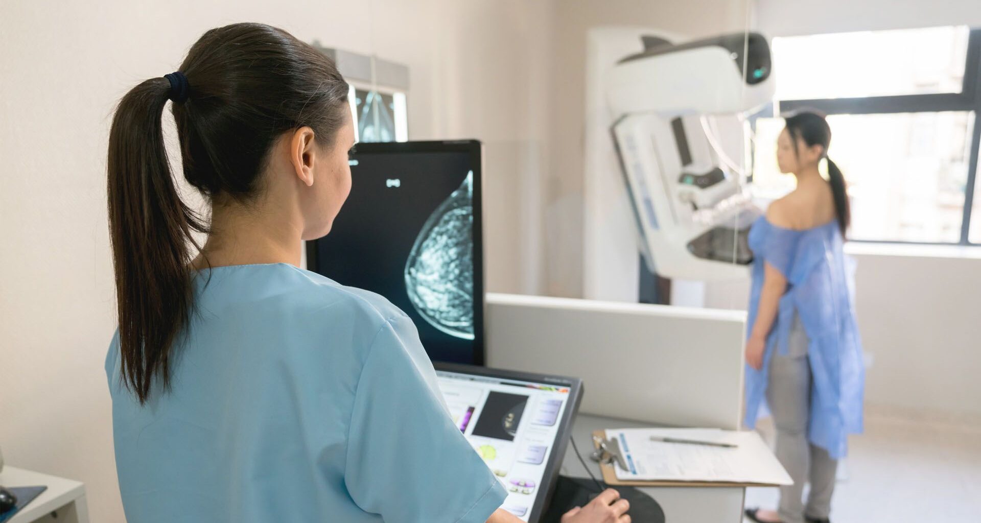 Nurse taking a mammogram exam to an adult patient at the hospital
