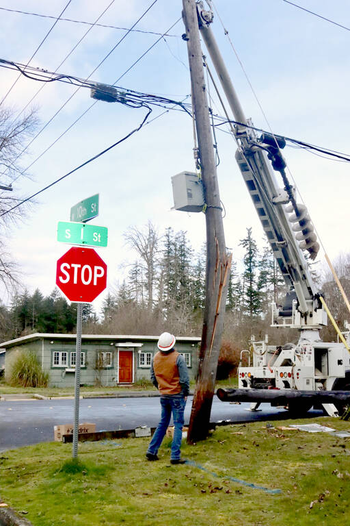 Richard Amundson of Astound looks at a broken utility pole at 10th and I streets in Port Angeles after it was hit by a car on Wednesday. The collision caused an outage of phone, cable and power for numerous homes on the west side of the city from about 9:30 a.m. until 7 p.m. as crews from the city of Port Angeles and Astound made repairs. (Dave Logan/for Peninsula Daily News)