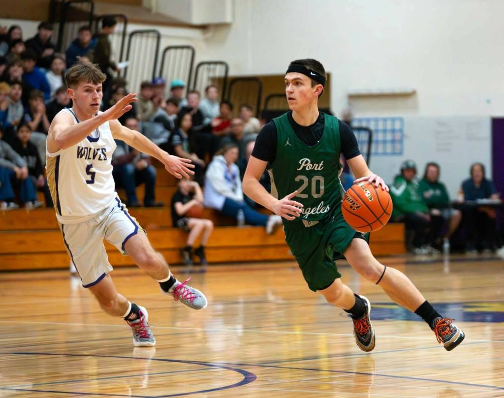 Port Angeles Ashton Gedelman brings the ball up the court against the defense of Sequims Mason Rapelje. Port Angeles won the loser-out District 3 tournament game in Sequim on Thursday 56-45. (Diamond Gentile/for Peninsula Daily News)