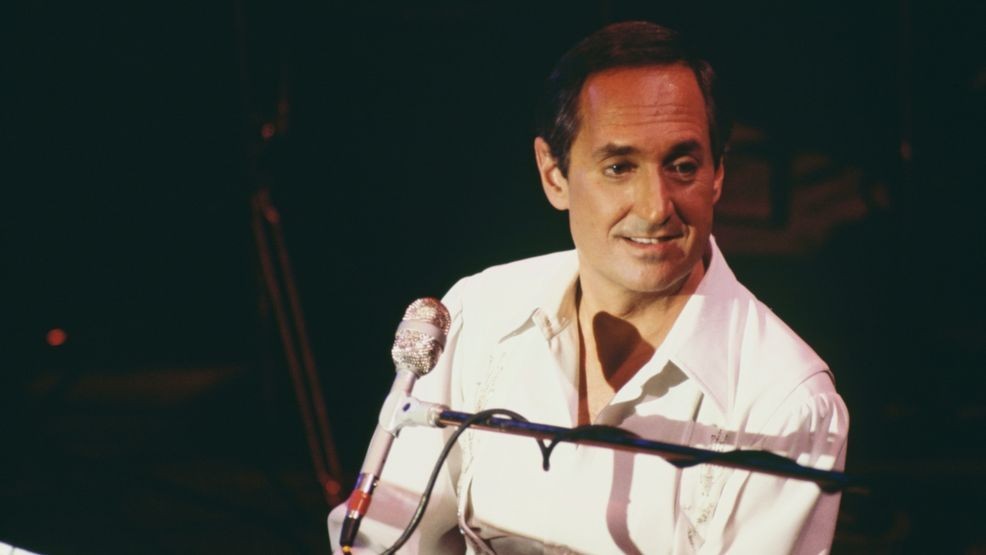American singer, songwriter and pianist Neil Sedaka sitting at a piano as he performs live in concert at a venue, 1986. (Photo by Keystone/Hulton Archive/Getty Images)