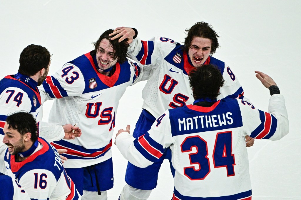 USA's #86 Jack Hughes (R) and USA's #43 Quinn Hughes (L) celebrates with teammates after winning the men's gold medal ice hockey match between Canada and USA during the Milano Cortina 2026 Winter Olympic Games.