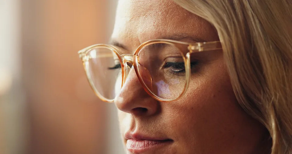 Person wearing clear glasses, looking thoughtful, close-up view