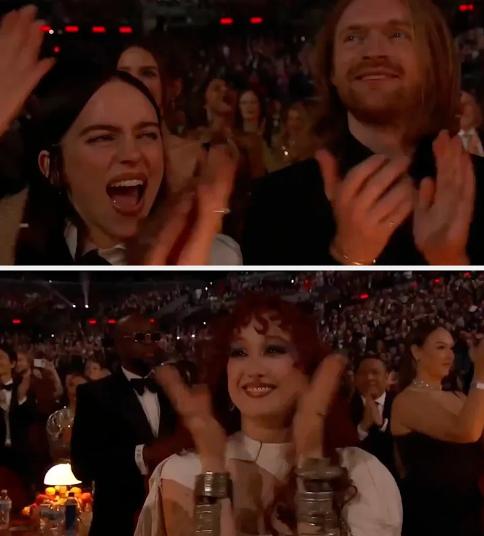 Two people clapping at an award show, seated in a lively audience