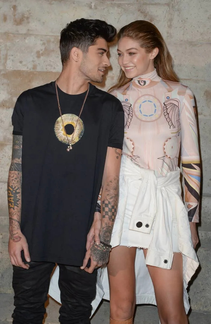 I don't know who these people are, but the man wears a printed T-shirt, and the woman wears a long-sleeve, futuristic-themed dress with a tied jacket