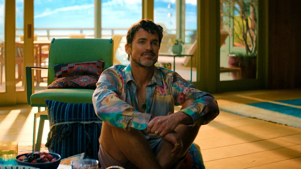 Man sitting on the floor in a modern room, wearing a patterned shirt and shorts