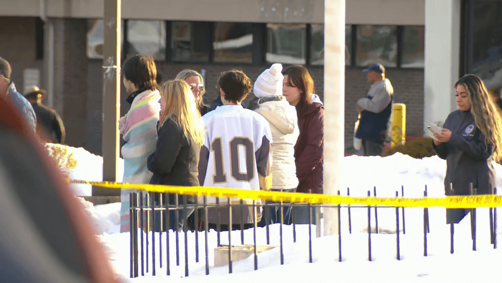 A person in a hockey jersey is shown with a group near the Dennis M. Lynch Arena in Pawtucket, where one person was killed and four were injured in a shooting, Monday, Feb. 16, 2026.