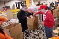 Chris Ortiz of Frisco and Carroll Ann Trotman of Columbus, Ohio pack food as volunteers...