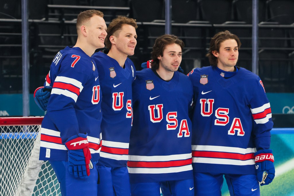 Four male ice hockey players from Team United States in blue jerseys with "USA" across the chest, posing together.
