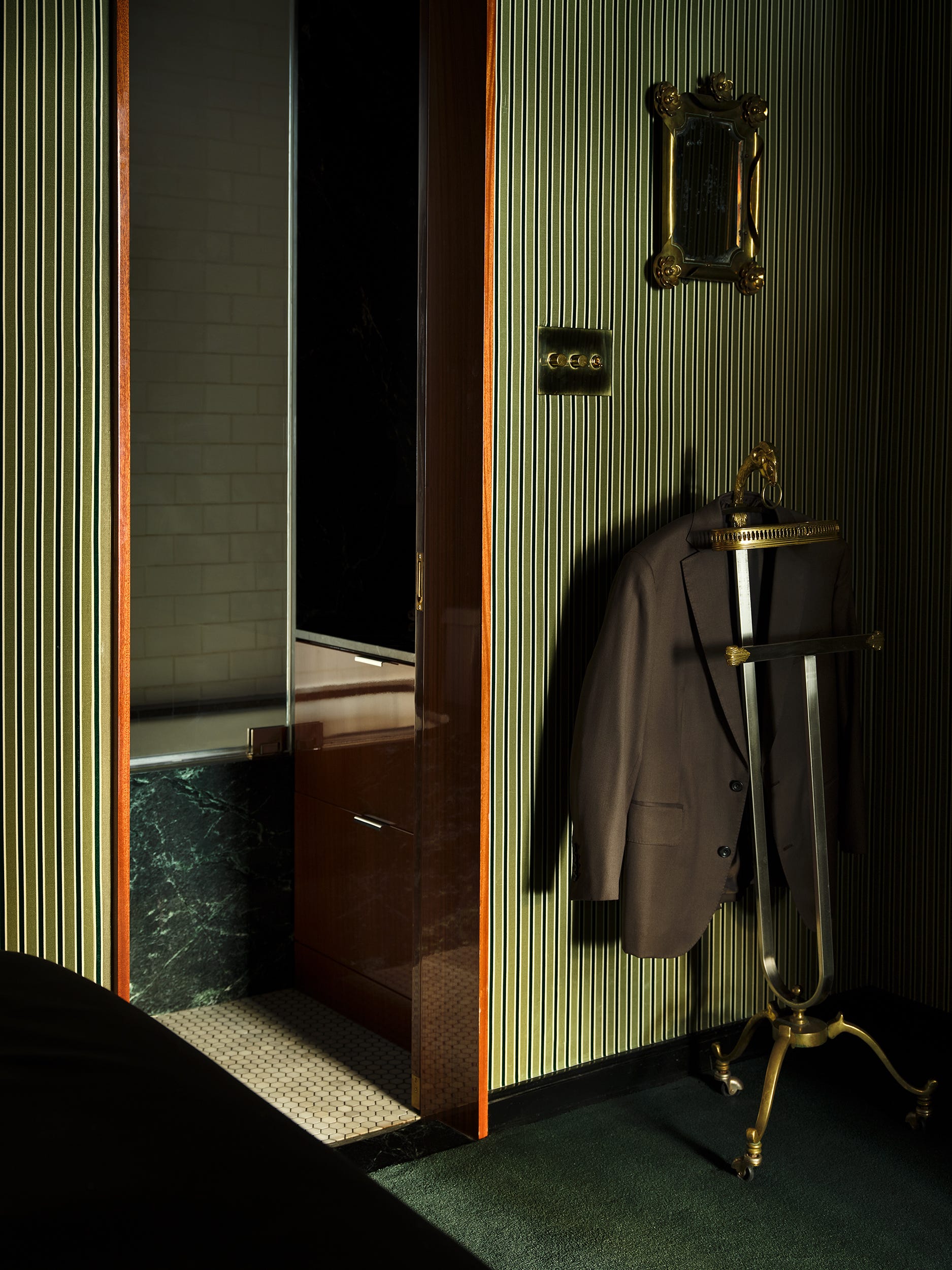 Interior of a stylish room featuring a doorway, a suit on a stand, and a decorative mirror.
