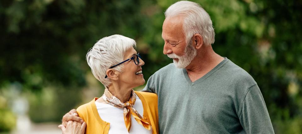 A happy older couple lean into each other, smiling.
