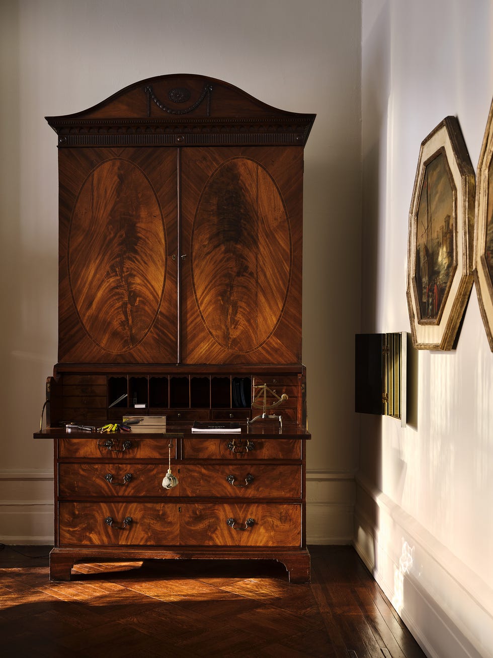 Antique wooden secretary desk with ornate details in a well-lit room.