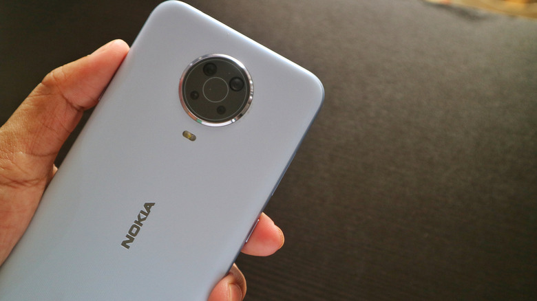 Person holding a white Nokia phone showing the phone's back