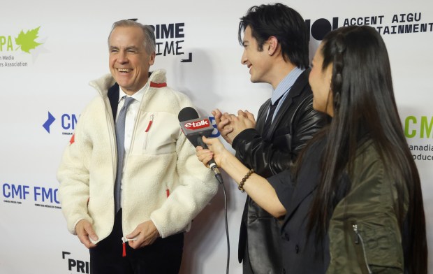 Hudson Williams, of the TV series "Heated Rivalry," presents Canadian Prime Minister Mark Carney with a fleece from the show on the red carpet at the Prime Time screen and media industry conference gala in Ottawa, Ontario, Thursday, Jan. 29, 2026. (Patrick Doyle/The Canadian Press via AP)