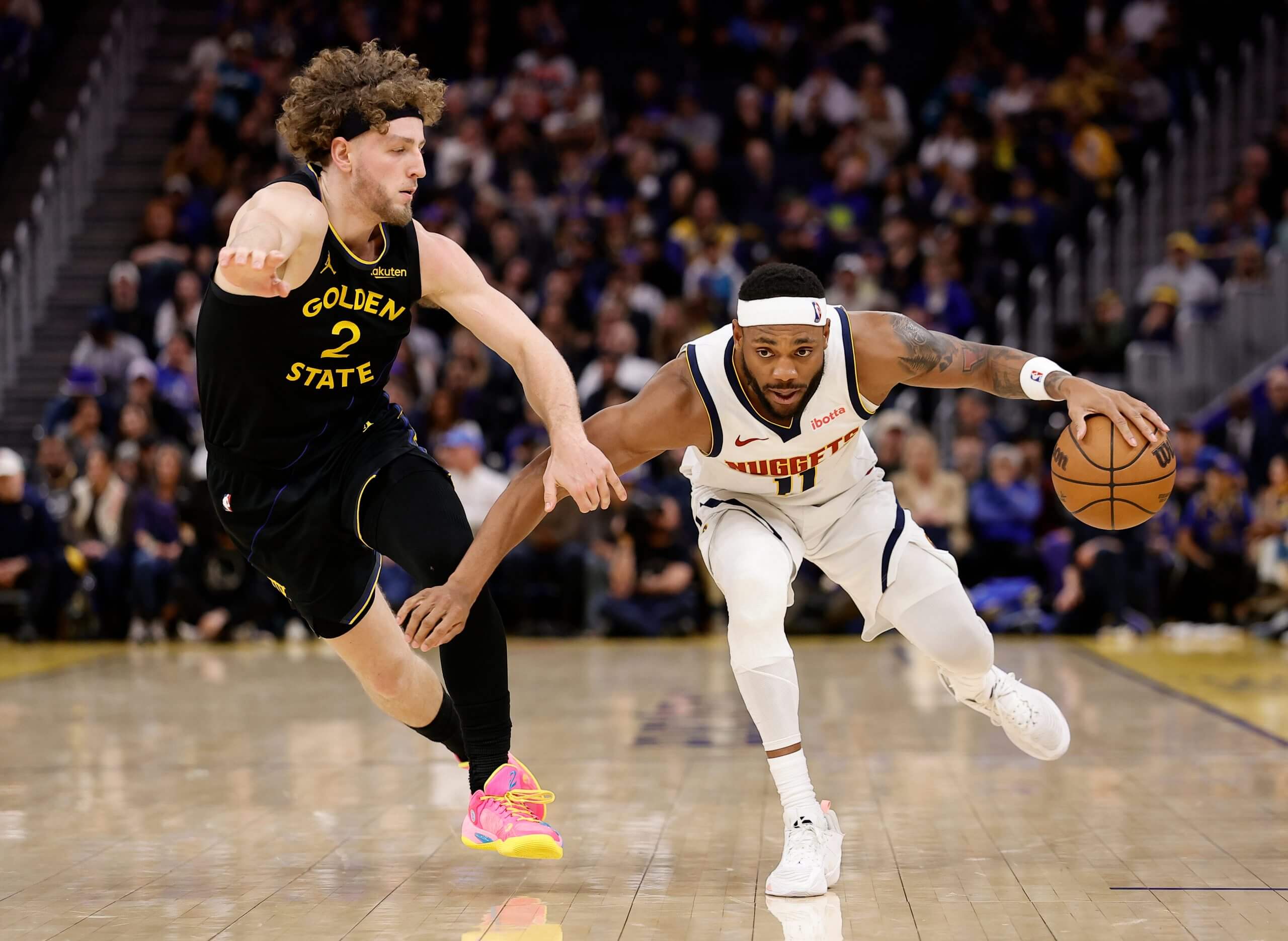Denver Nuggets forward/guard Bruce Brown controls the ball against Golden State Warriors guard Brandin Podziemski during the second half of an NBA basketball game, Sunday, Feb. 22, 2026, in San Francisco.