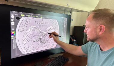 Medallic artist Eric David Custer at his workstation, showing his design for the tails side of the semiquincentennial dime on a computer screen.