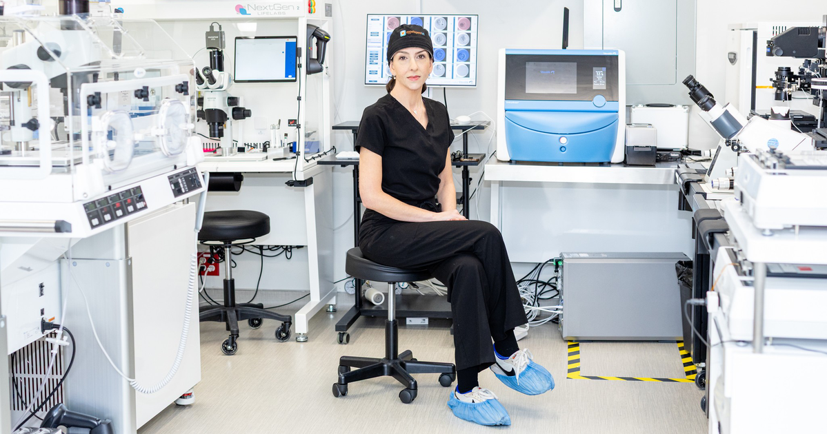 A bobblehead figure of a smiling woman in a white coat and black dress stands on a shelf labeled “Egg Whisperer,” surrounded by books and a white unicorn figurine.