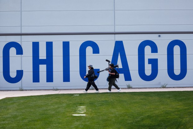 Members of the press walk past a Cubs logo on a practice building at spring training on Feb. 18, 2026, at Sloan Park in Mesa, Ariz. (Armando L. Sanchez/Chicago Tribune)