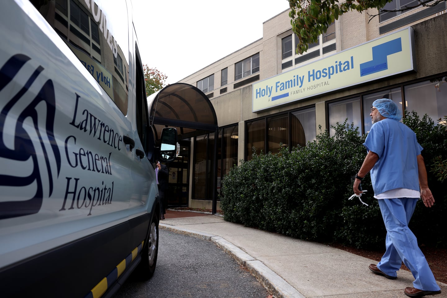 A staff member walks past a sign for Holy Family Hospital in Methuen, with a reference to Steward Health Care covered up following its takeover by Lawrence General Hospital, in 2024.