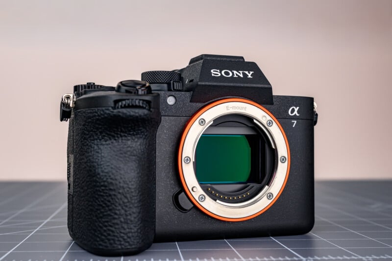 A Sony Alpha 7 mirrorless digital camera body without a lens, showing the E-mount and sensor, placed on a gray grid-patterned surface with a neutral background.