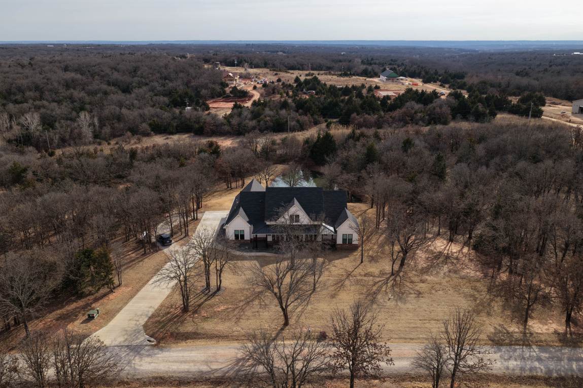 An aerial photograph of a large house surrounded by trees, with other houses in the distance.