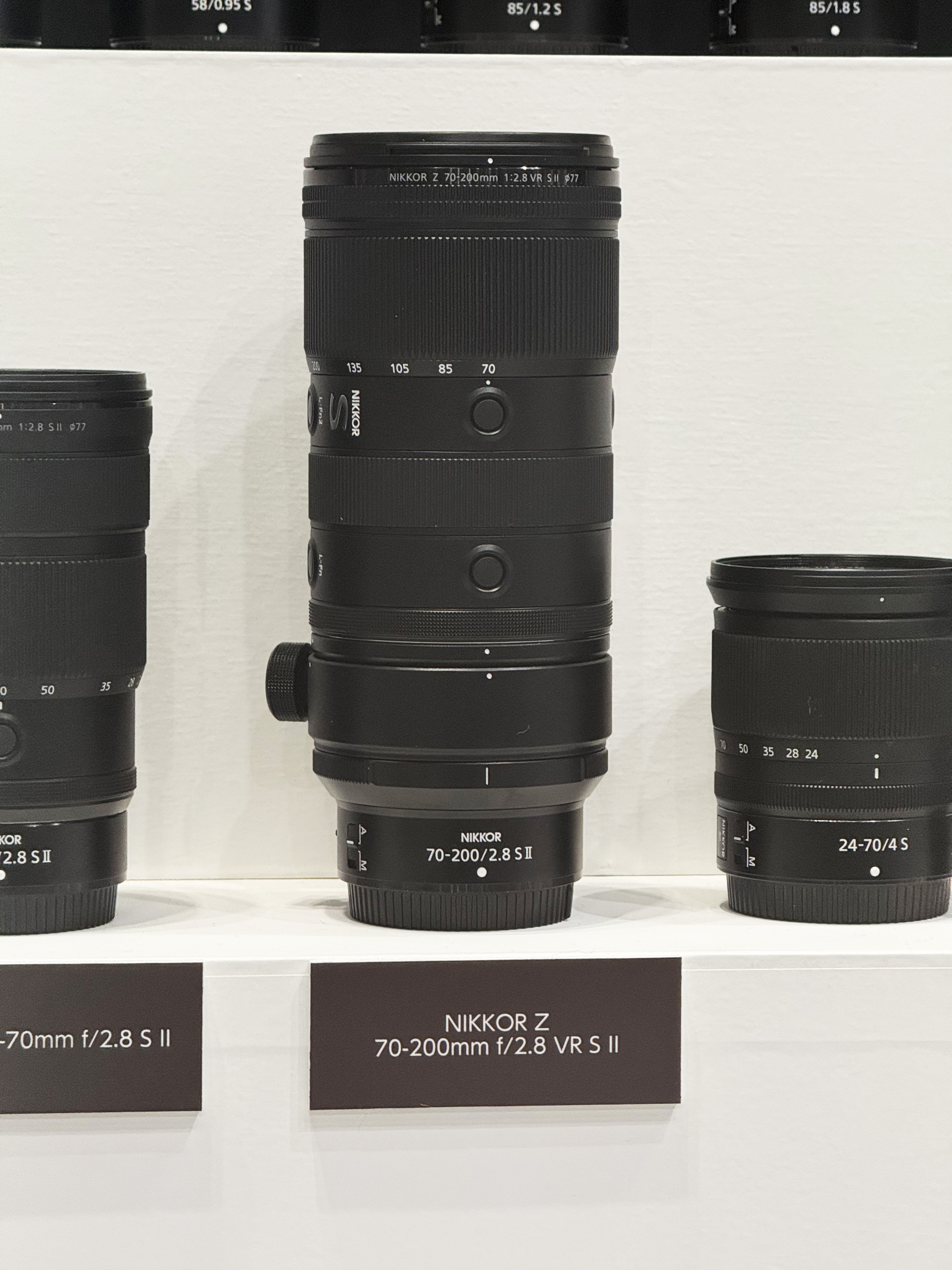 Nikon Z 70-200mm f/2.8 VR S II lens on a display at a photography show, alongside two other Nikon lenses
