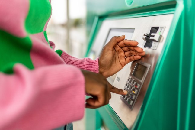 Unrecognizable young adult african woman hand entering personal identification number on ATM dial panel - Millennial person withdrawing money at automatic ATM machine typing secret security code number