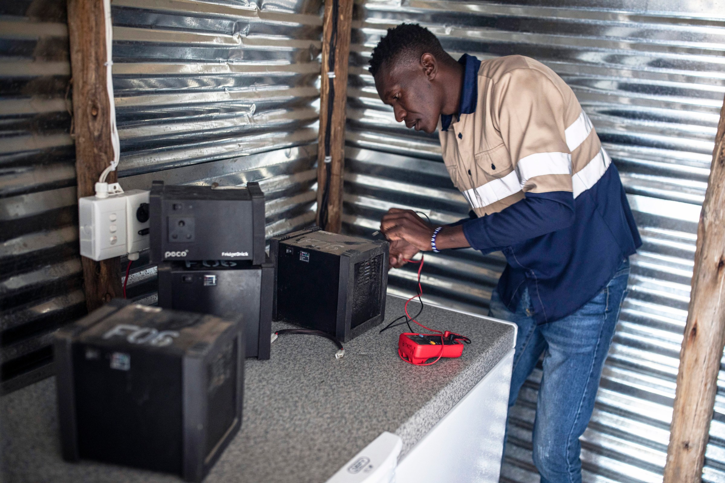 A technician repairing power brick units for a solar powered fridge