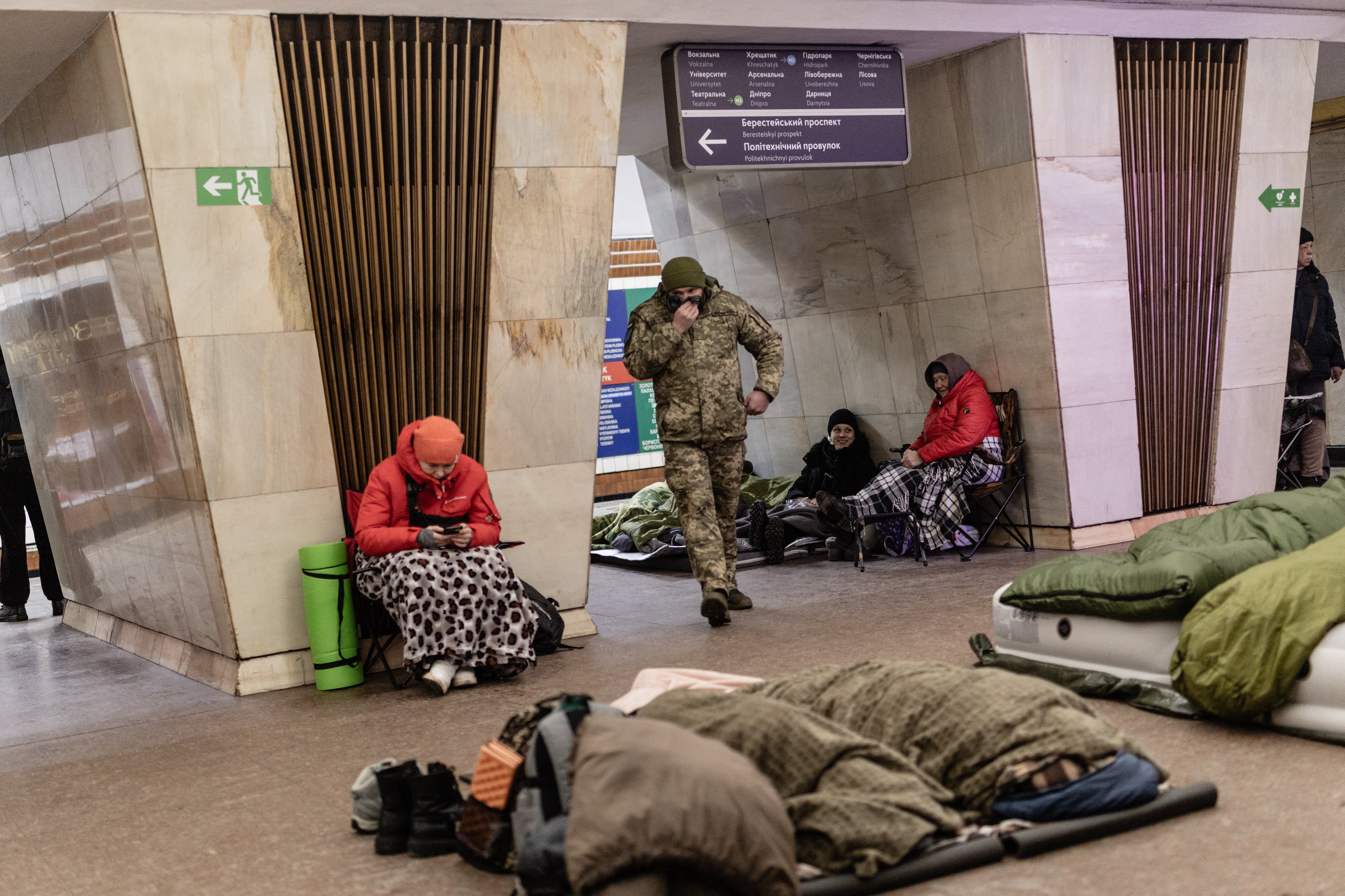 People sit on folding chairs while others sleep on the floor with sleeping bags as a man in military uniform walks past, in Kyiv, Ukraine on February 7, 2026. Civilians gathered in metro stations with bedding and basic supplies to seek safety during nighttime air attacks on the city. (Photo by Daniel Yovkov / Hans Lucas / AFP via Getty Images)