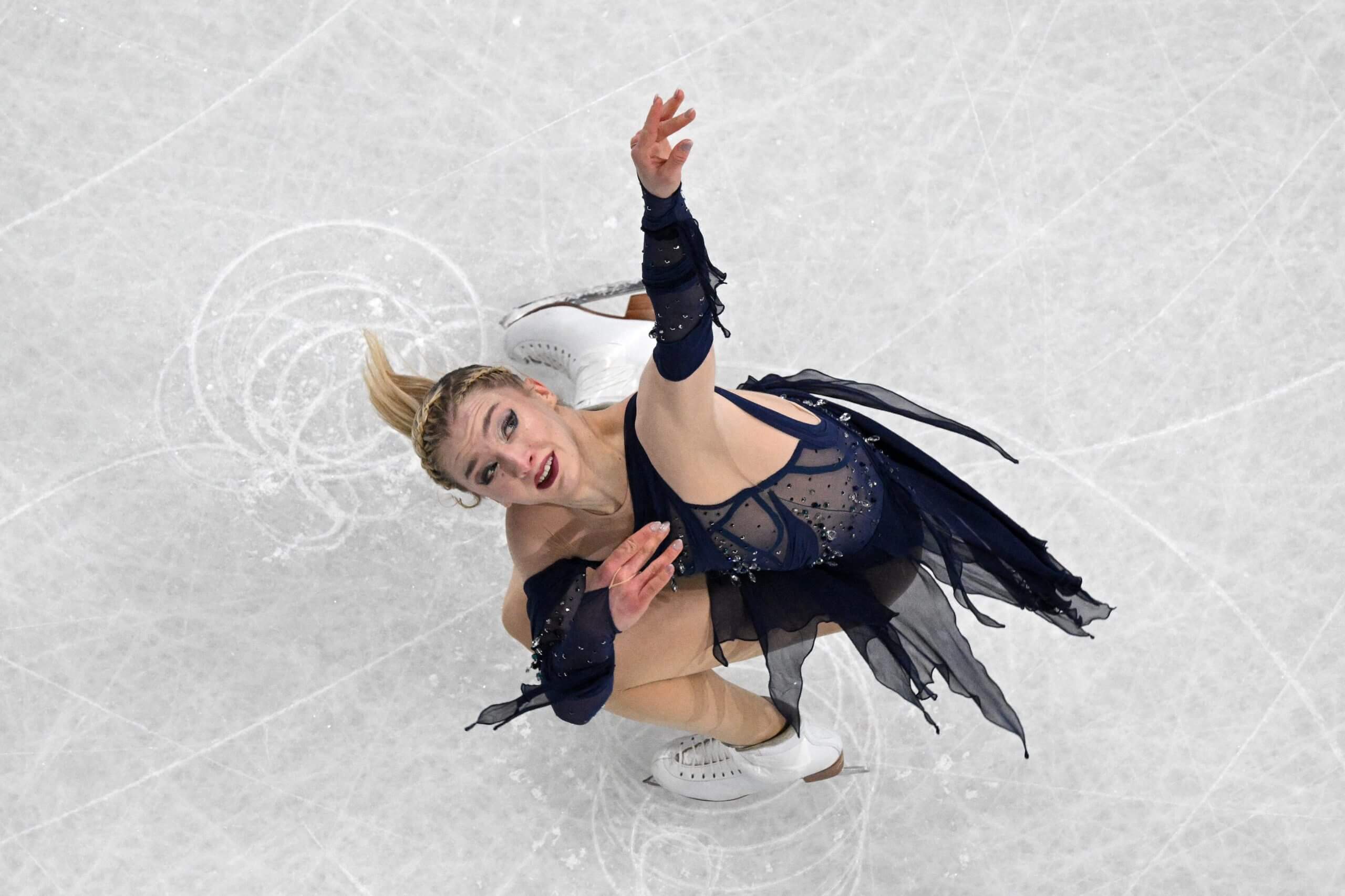 Amber Glenn, wearing a navy one-shoulder dress and looking skyward, competes in the women's free skate portion of the team event.