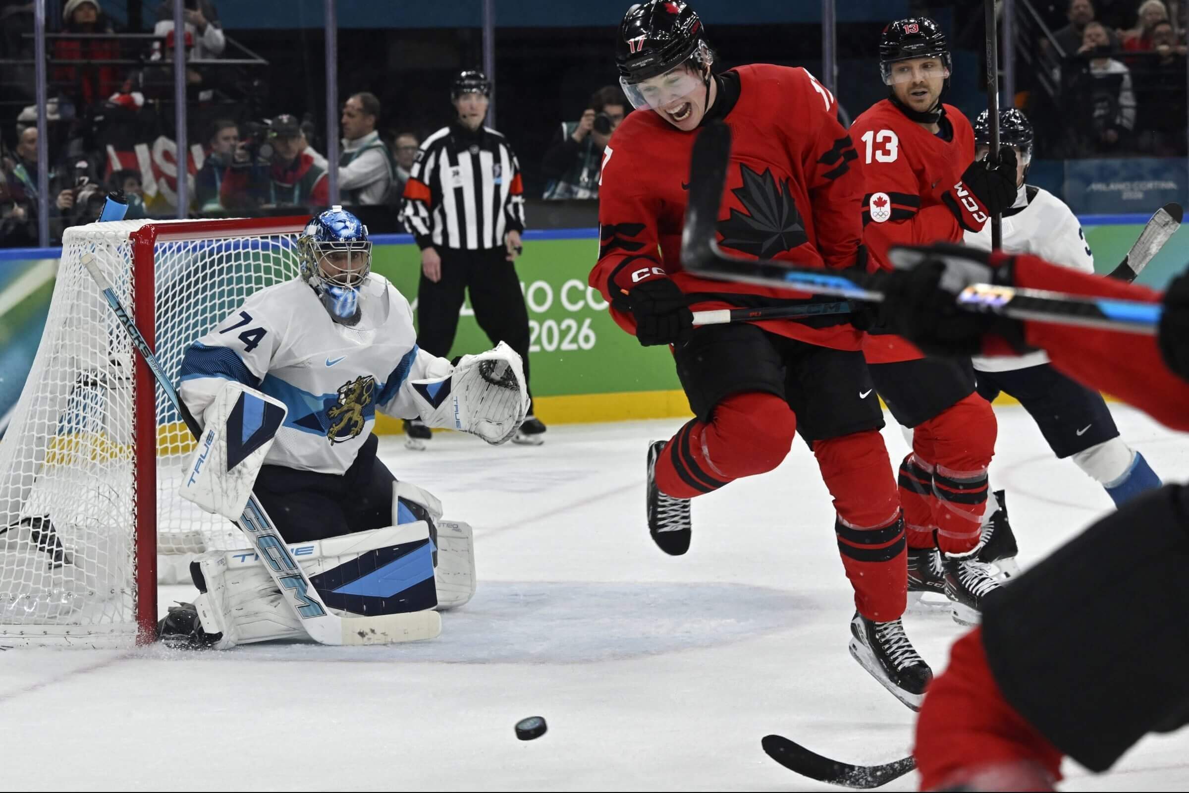 The puck that resulted in the winning score travels toward Finland goalie Juuse Saros, in a white jersey.