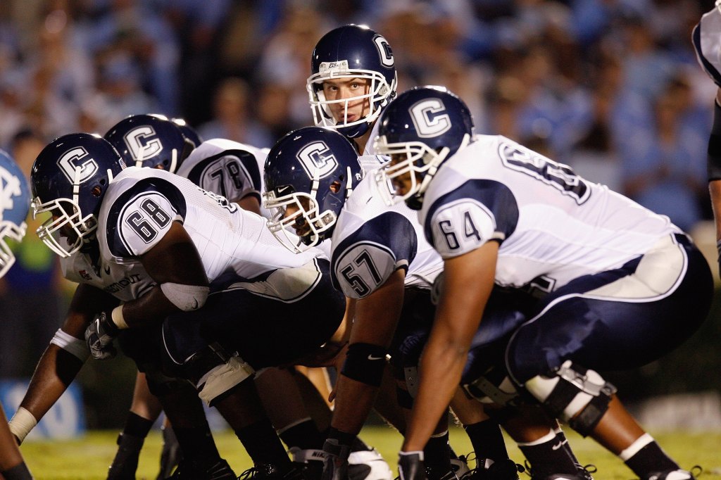 Football players in navy and white uniforms at the line of scrimmage.