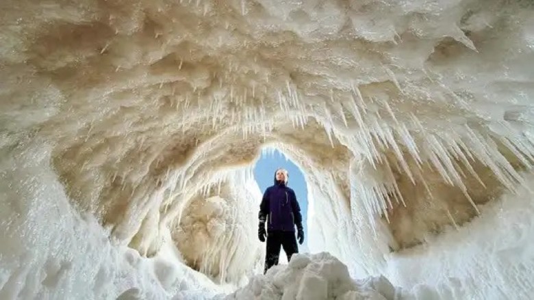 A woman stands in the entrance to an ice cave