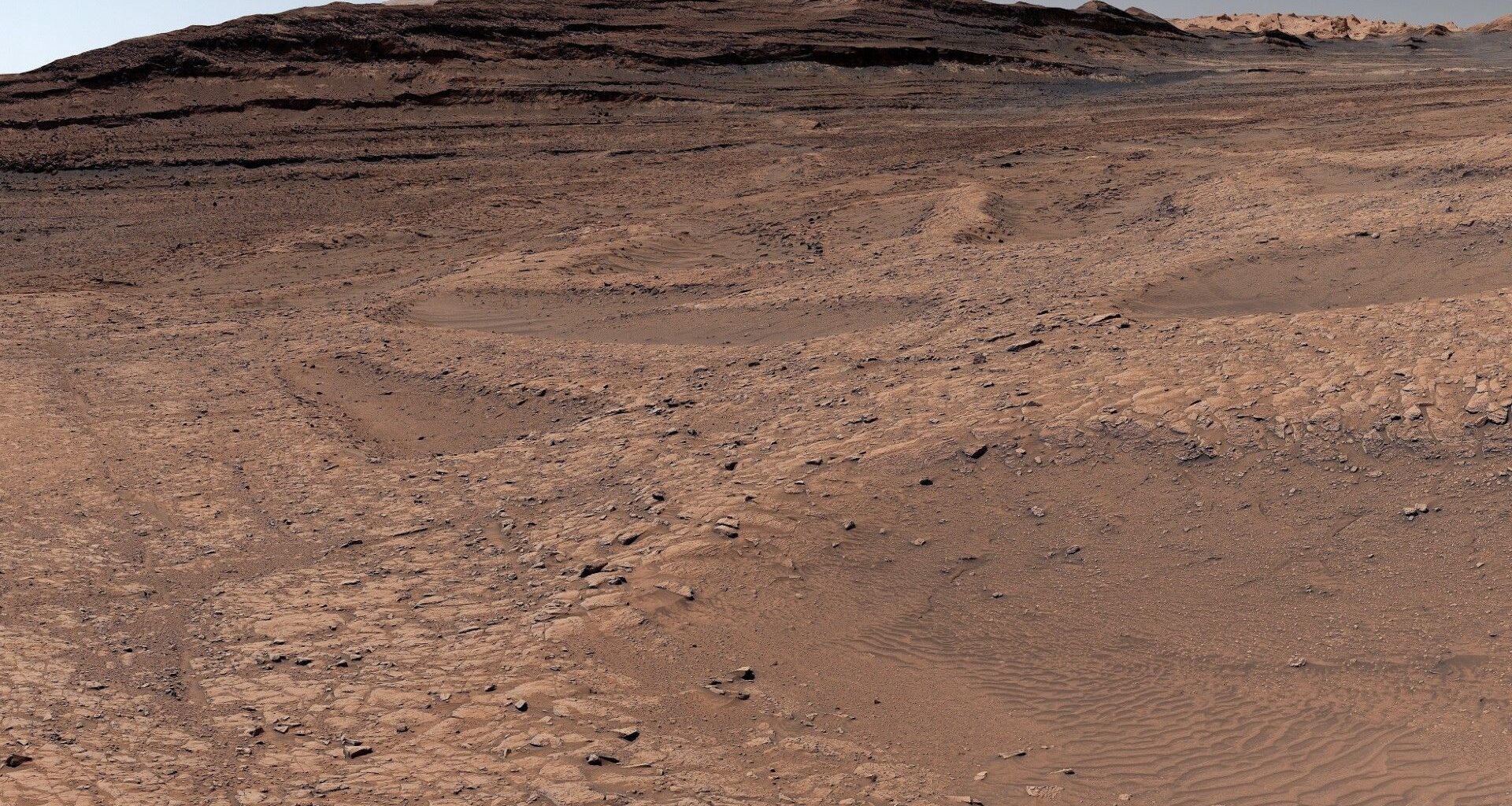 a red, dusty landscape with shallow ravines carved throughout it