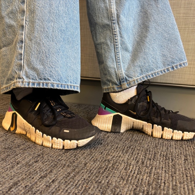 A close-up photo of someone wearing black Nike Free Metcon 6 sneakers.