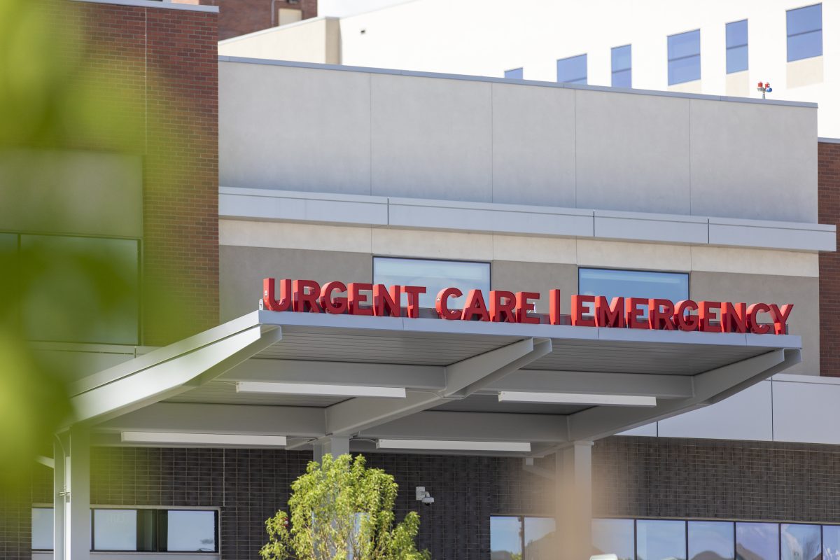 Exterior view of a building with a red sign indicating "Urgent Care | Emergency" above the entrance.