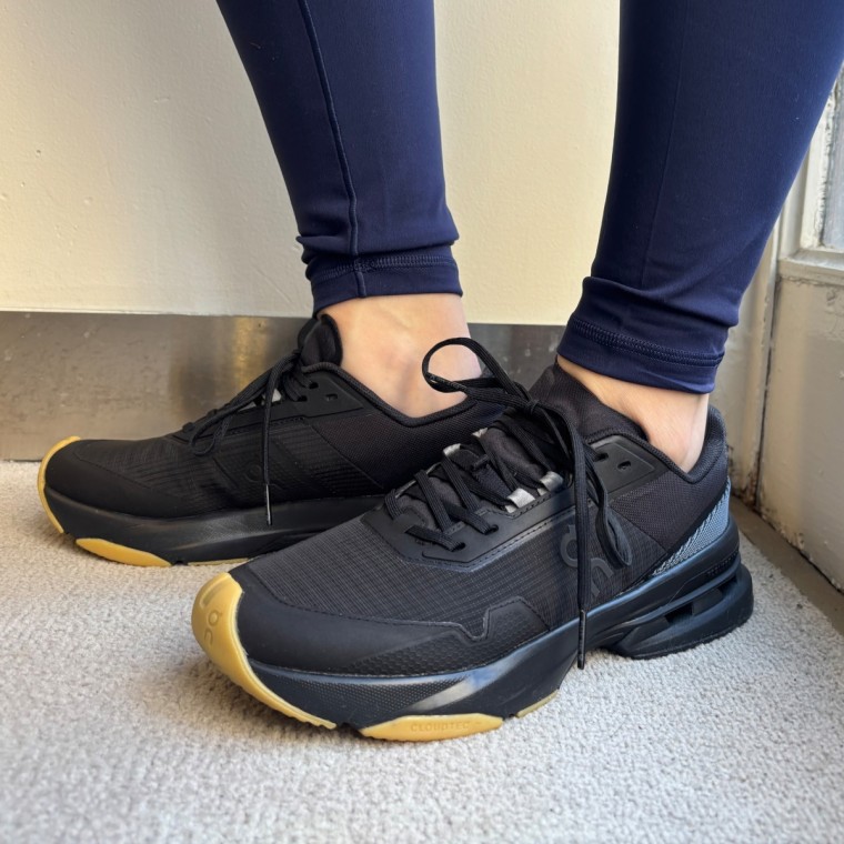 A close-up photo of someone wearing black On Cloudpulse Pro training sneakers.