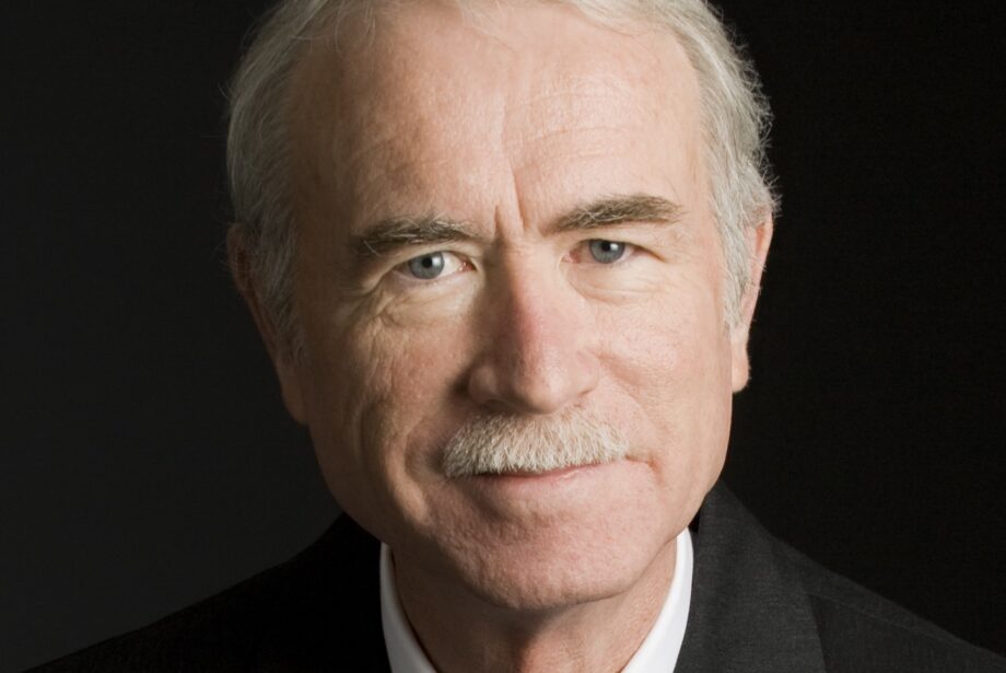 A business headshot of Greg Roberts, a retired architect, in a suit and tie