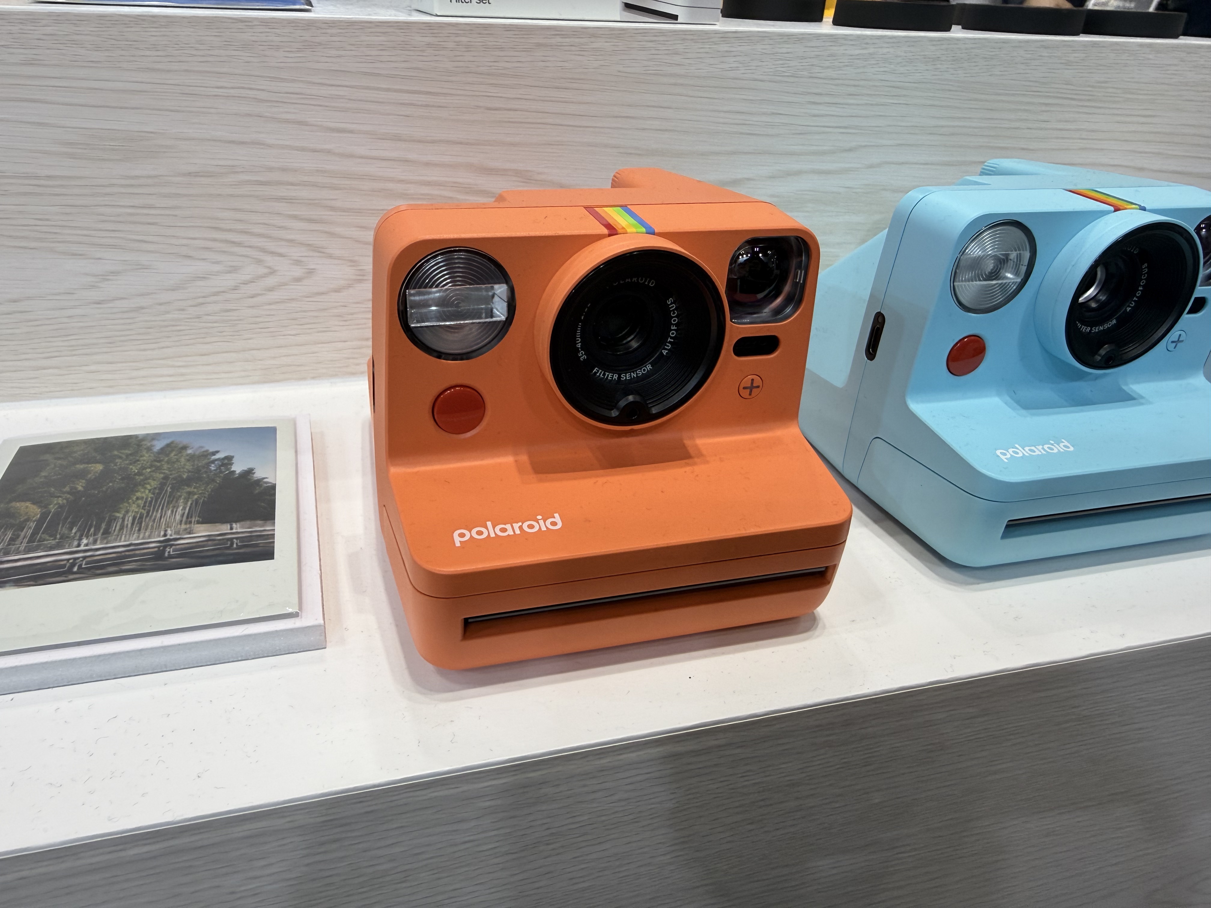 An orange polaroid camera on display at the CP+ 2026 show