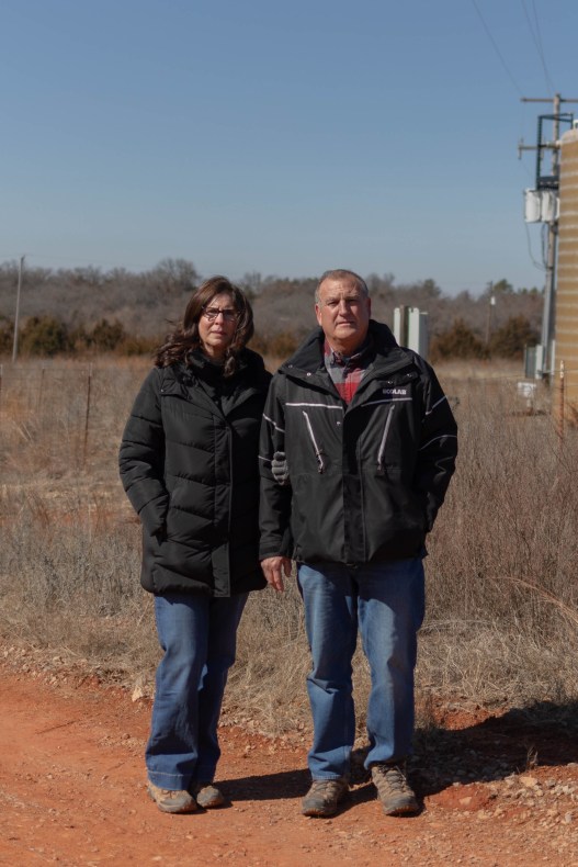 A man and a woman stand side by side on a dirt road.