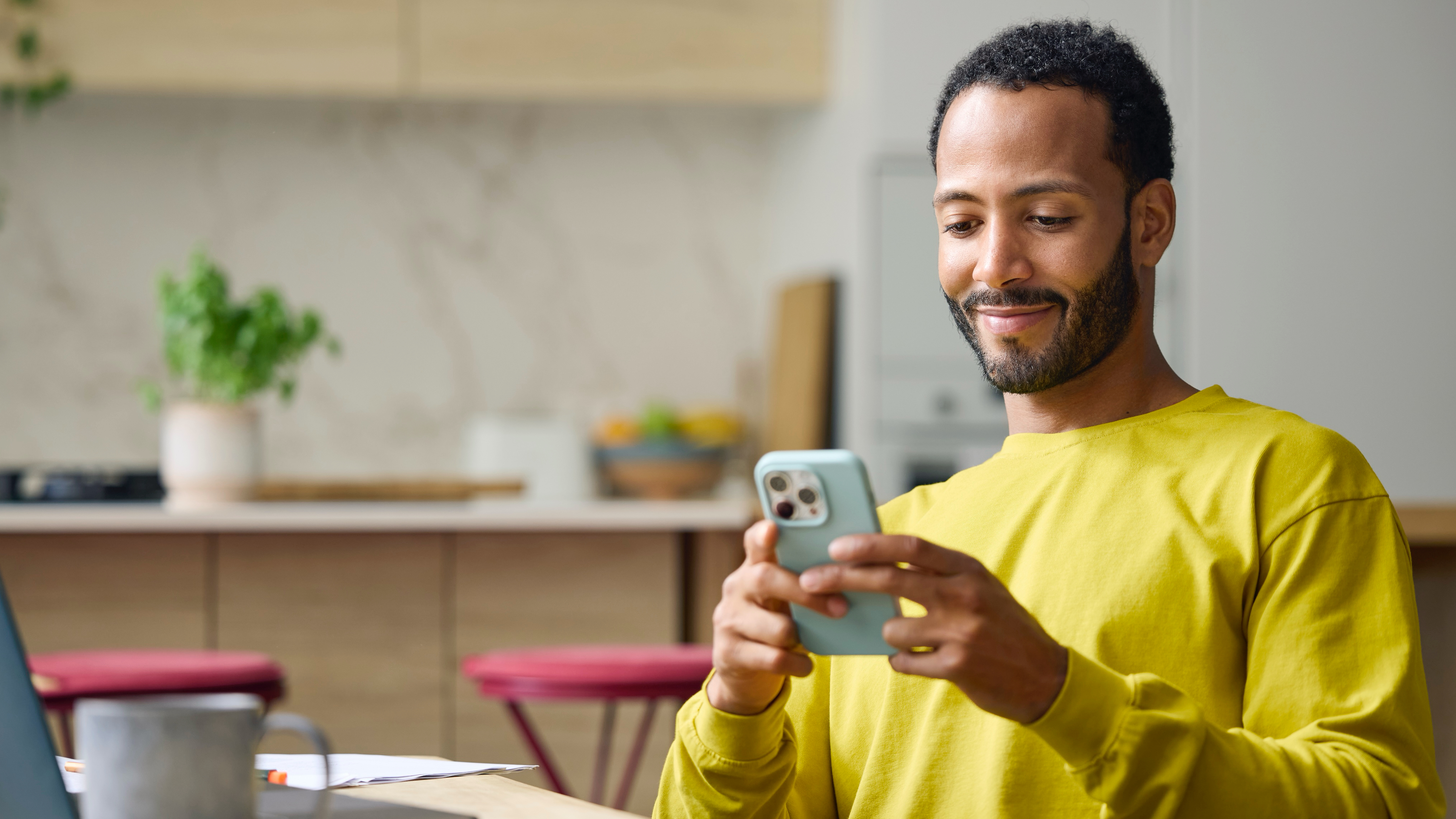 Man in a yellow sweater using a smartphone